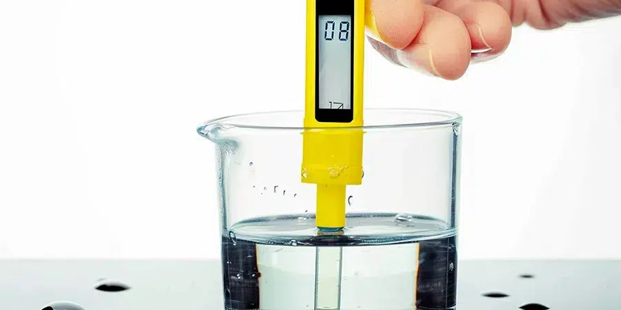A pH meter inserted into a container of water, displaying the pH level to help growers monitor the water's pH balance, ensuring it is within the ideal range for cannabis cultivation.